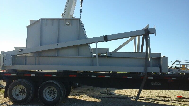Heavy steel assembly loaded on a flatbed under crane