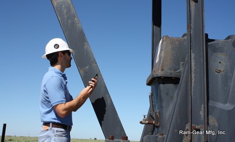 Technician reviewing a unit on a phone beside a pumping unit